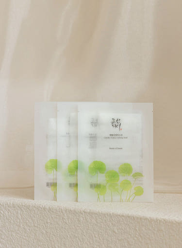 Beauty of Joseon Centella Asiatica Calming Mask 25ml x 10ea in white packets with green centella leaf illustrations, arranged on soft beige surface